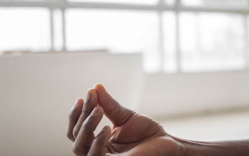Person meditating in a bright, sunlit room, focusing on breathing.